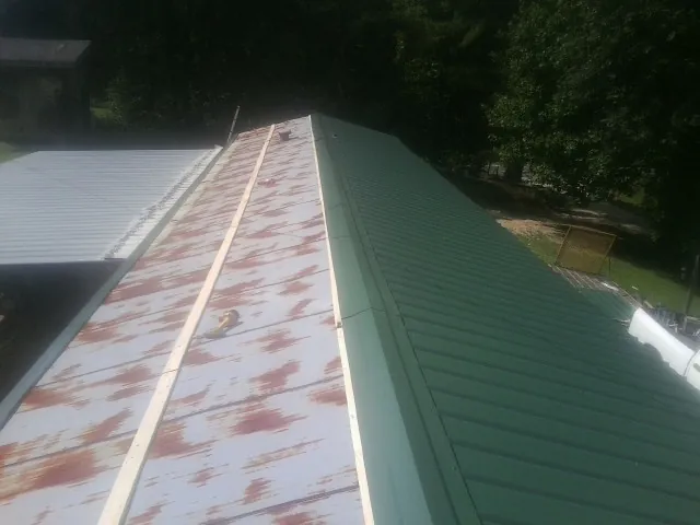 Old rusted panels beside newly installed green metal roofing — Wind Damage Roof Repair by Roofing Brothers in Mendon