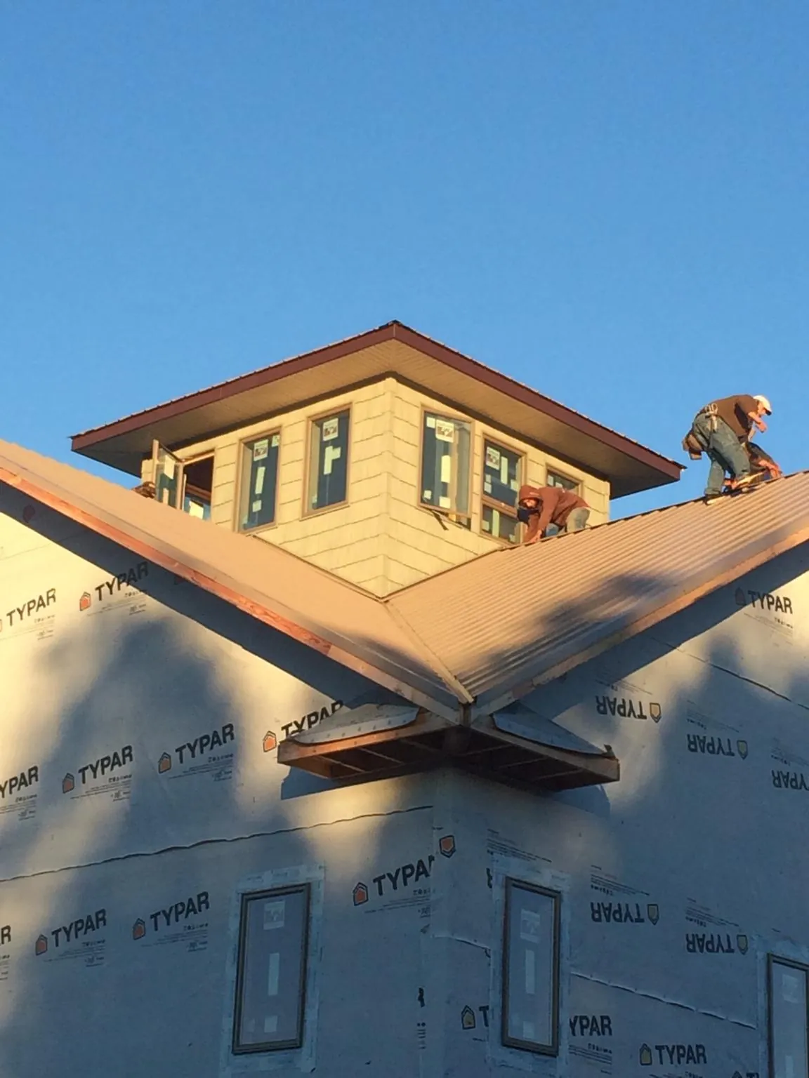 Roofers working around a rooftop cupola on a new metal roof at sunset — Roof Waterproofing in Mendon by Roofing Brothers